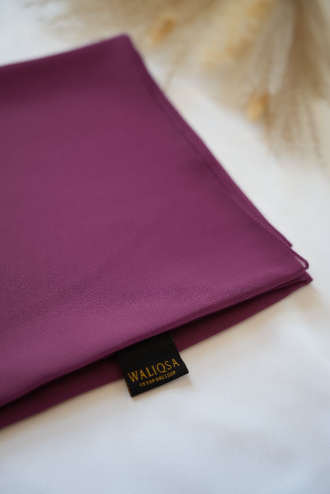Dark lavender chiffon hijab folded neatly on white background, showing soft texture.