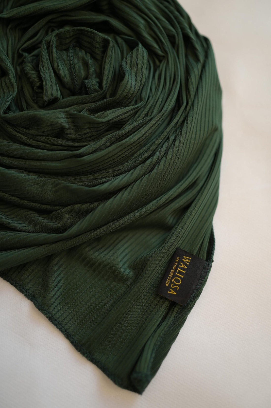 Green jersey hijab folded neatly with soft texture on clean white background.

