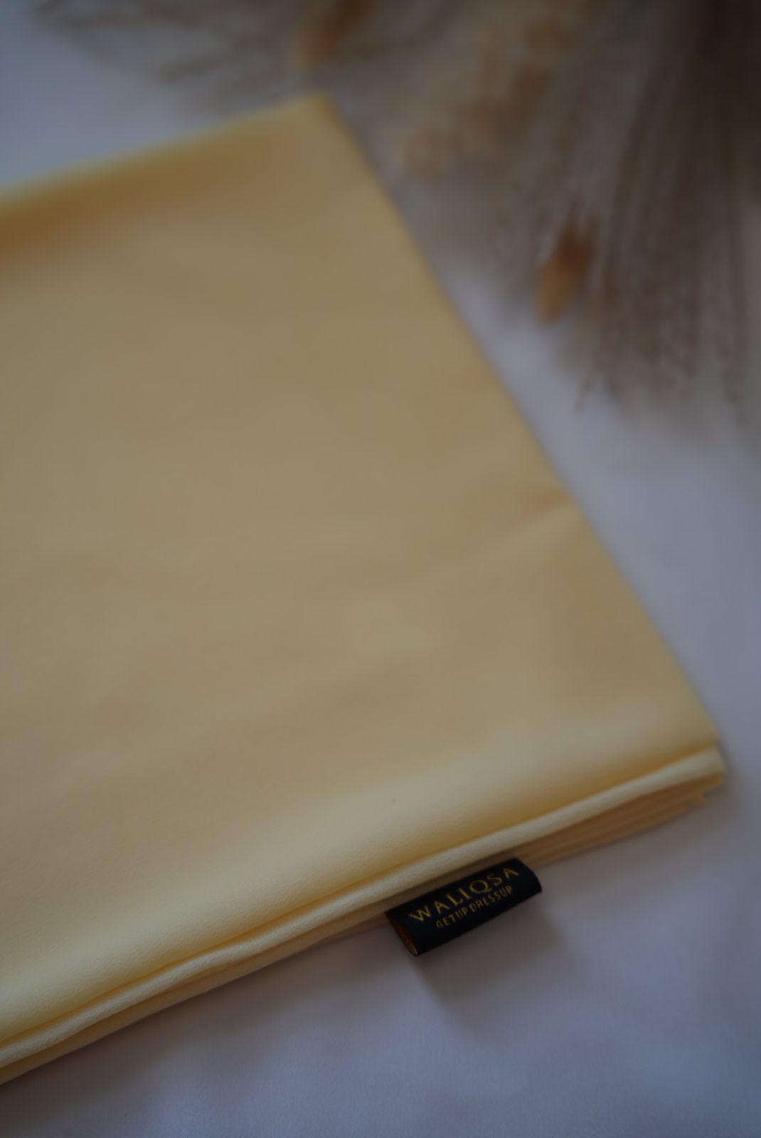 Sunlight yellow chiffon hijab folded neatly with soft texture and breathable fabric.

