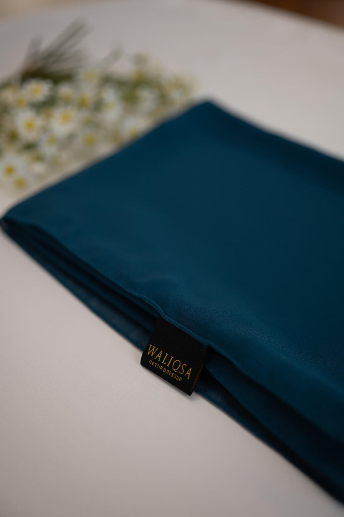 Tosco-colored chiffon hijab folded neatly, showcasing soft and airy fabric.

